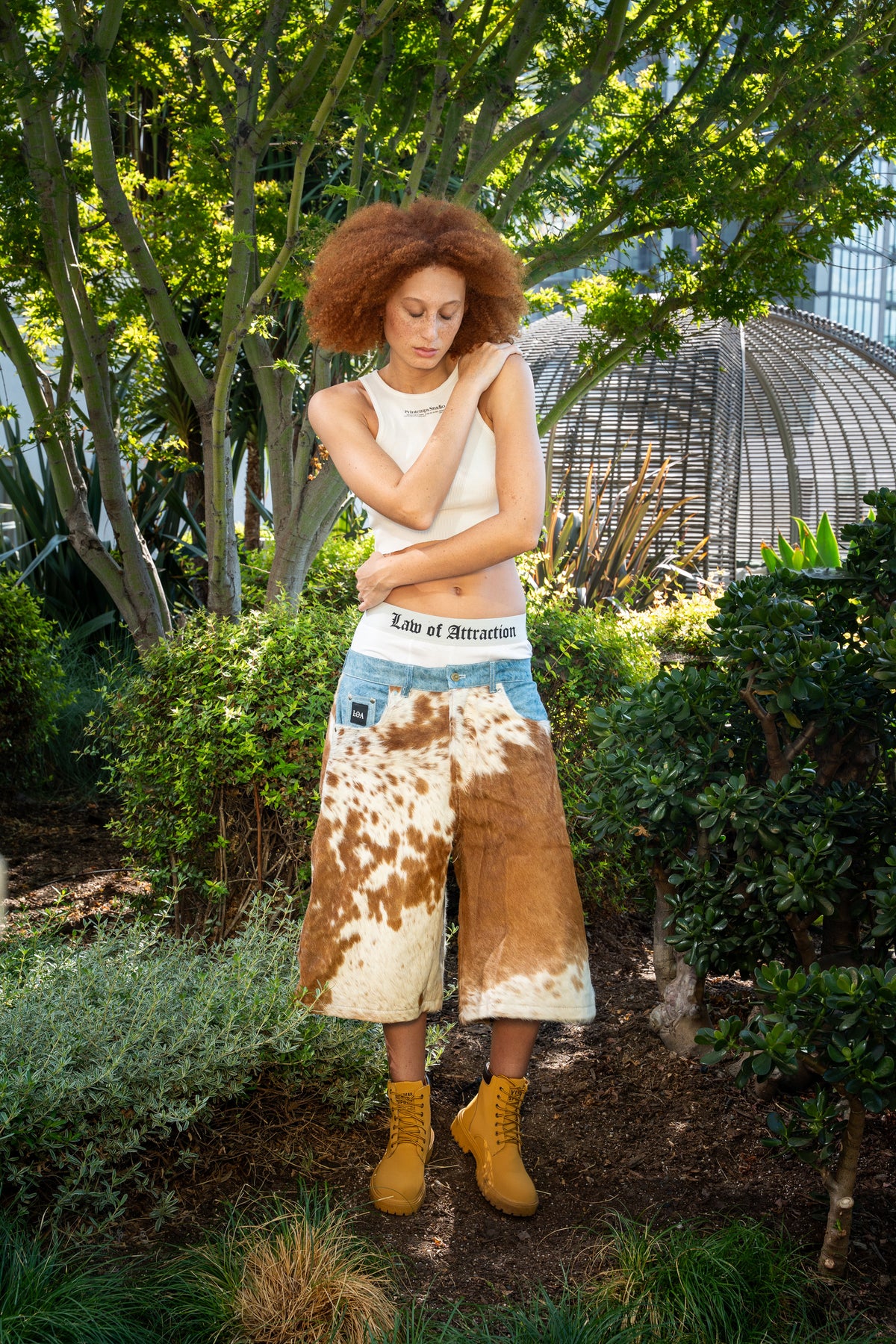 Brown and ivory cowhide denim shorts worn outdoors — front natural hide pattern