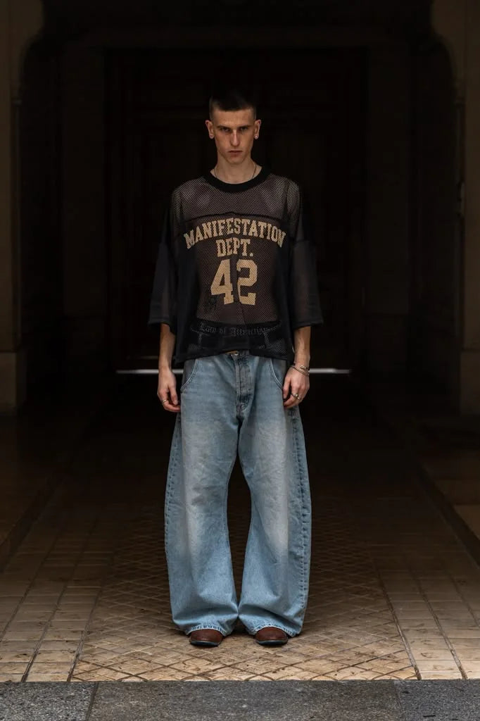 Model wearing Manifestation Dept football jersey and denim