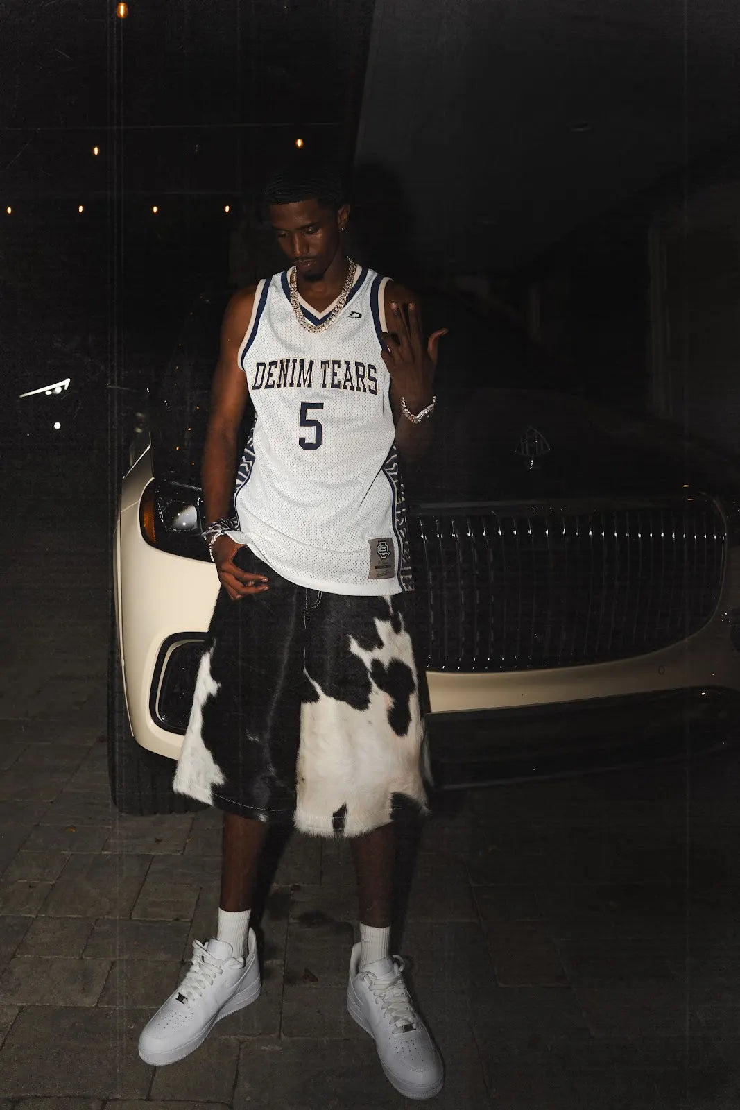 Christian Combs looking down at his outfit, showing the cowhide pattern and denim waistband of the jorts.